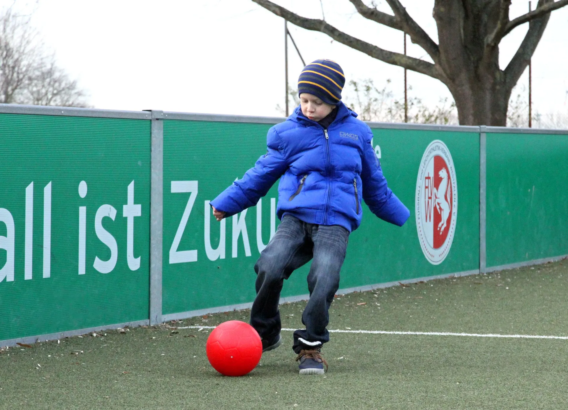 eine Junge spielt mit einem roten Ball auf einem Soccerplatz