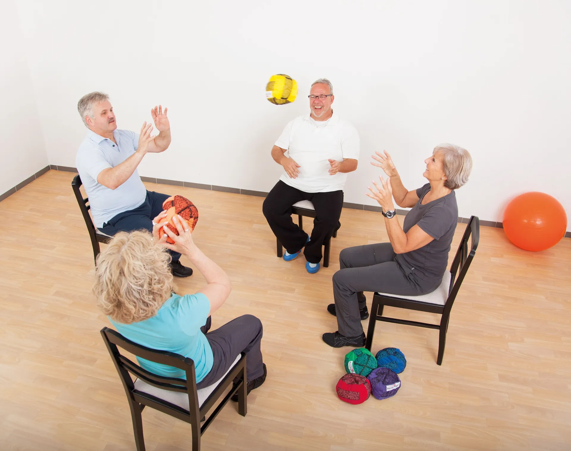 Seniorengruppe beim Sitzkreis-Gleichgewichtstraining mit Bällen zur Förderung von Koordination