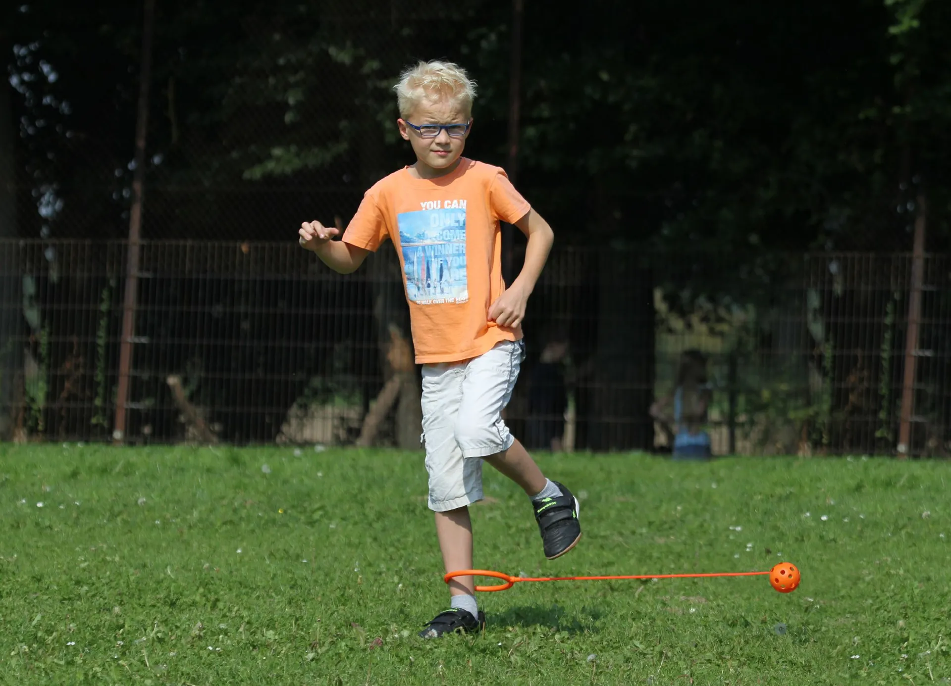 Junge spielt mit einer Fußkugel auf der grünen Wiese