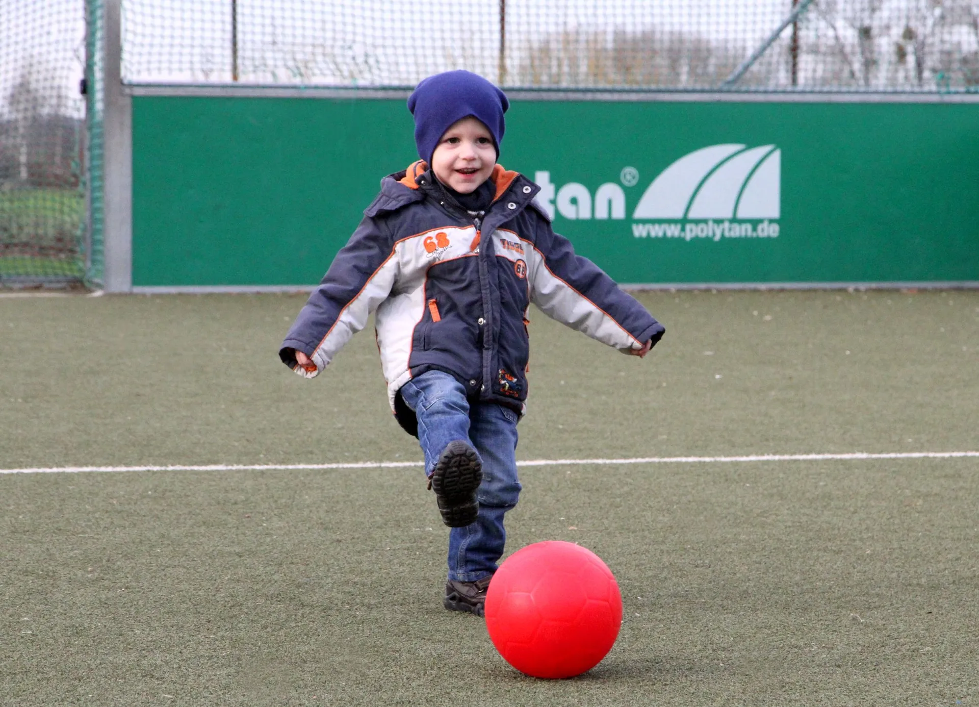 eine Junge schießt einen roten Ball auf einem Soccerplatz